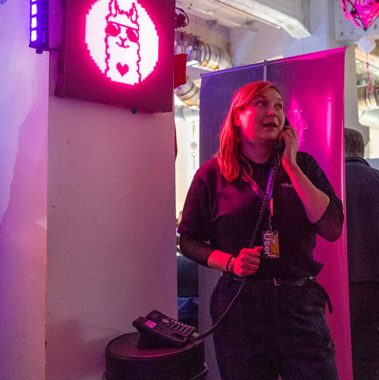 Kyberturvallisuuskeskuksen erityisasiantuntija kuuntelee viestiä lankapuhelimen luurista pinkkien neonvalojen hohteessa.