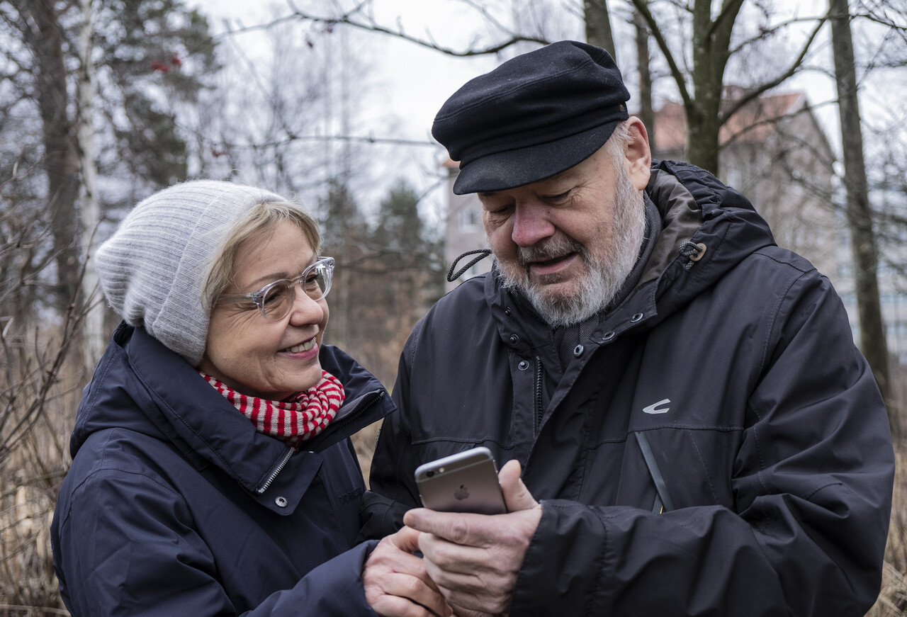 Seniori-ikäinen nainen ja mies katsovat yhdessä älykannykkää.